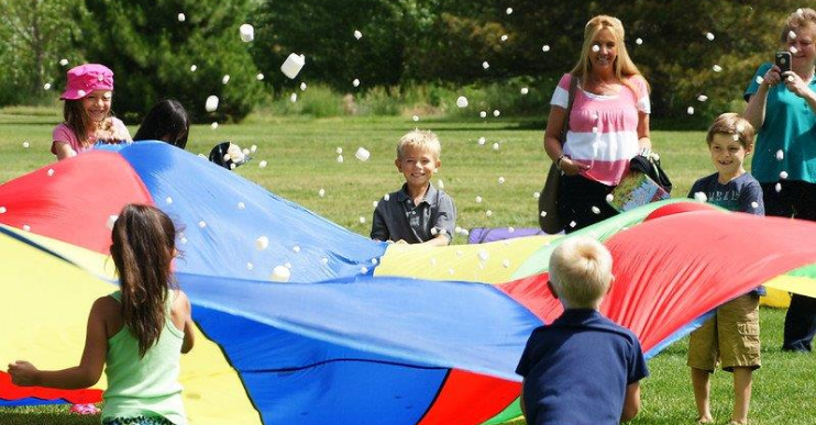 Children play with a parachute and bubbles