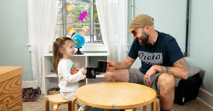 A father sits with his daughter in her child care center