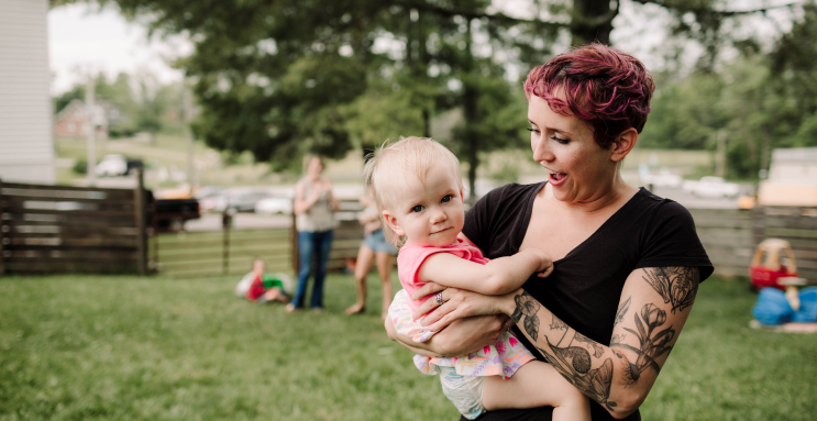 An early childhood educator holds a small child outside