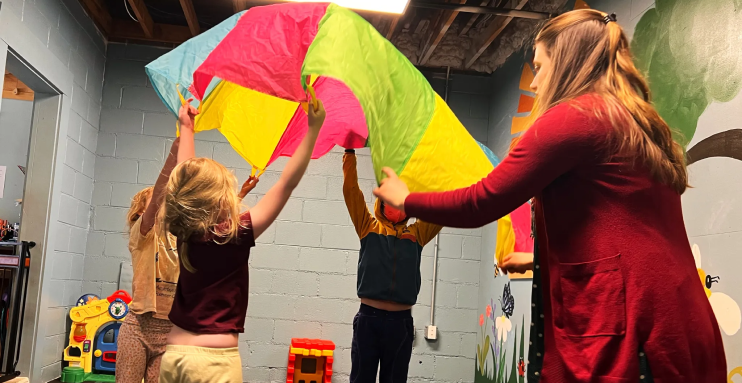 Children and teacher play with a parachute